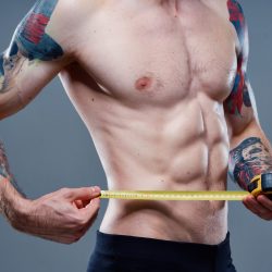 athlete with pumped up arm muscles and tattoos bodybuilder fitness centimeter tape. High quality photo
